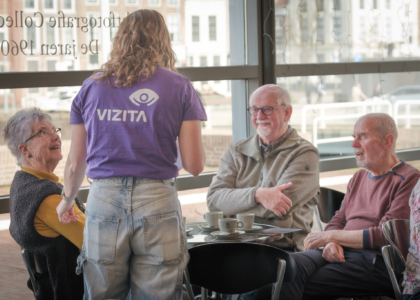 Een jongere praat met ouderen in een café.