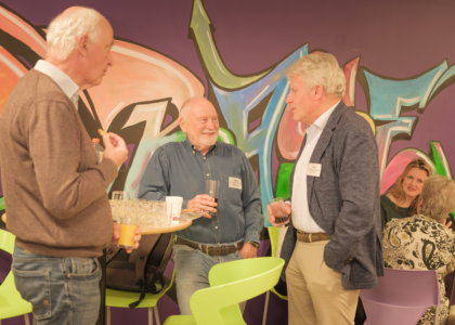 Drie mannen in gesprek met kleurrijke graffiti op de achtergrond.