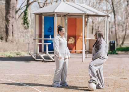 Twee vrouwen in sportkleding praten op een voetbalveld.