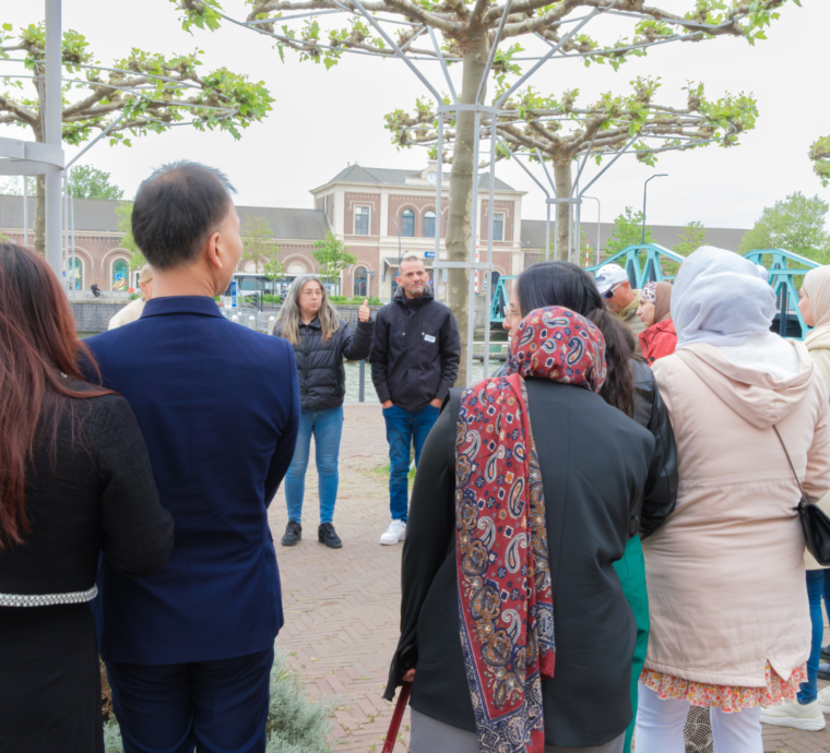 Groep mensen luistert naar een spreker in een park.