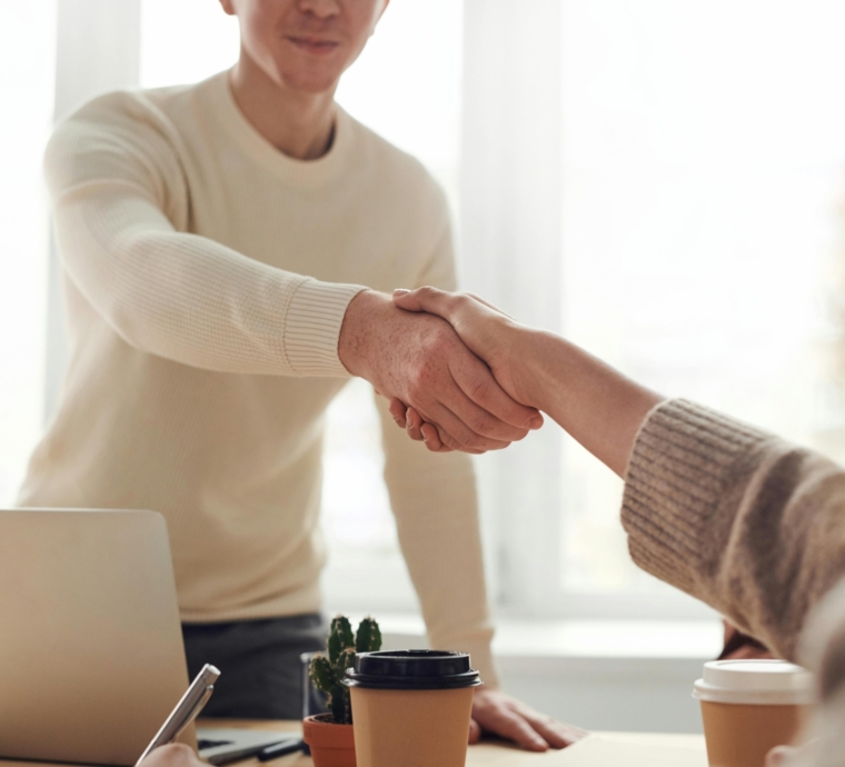 Twee mensen schudden handen tijdens een zakelijke ontmoeting.