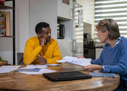 Twee mensen bespreken documenten aan een houten tafel