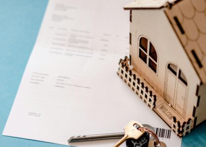 Sleutels en een houten huisje op een document.