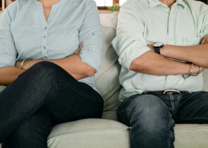 Een man en vrouw zitten met gekruiste armen op een bank.