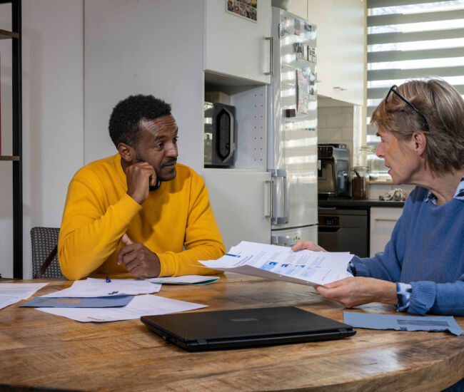 Twee mensen bespreken documenten aan een houten tafel