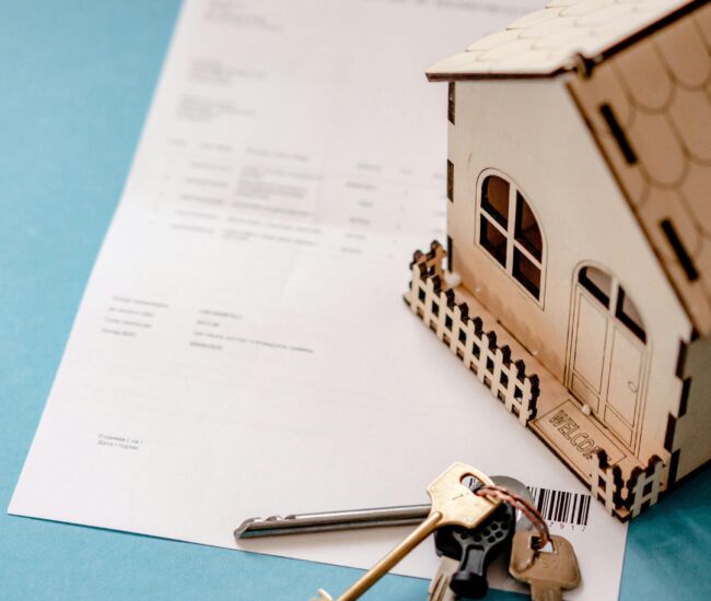 Sleutels en een houten huisje op een document.