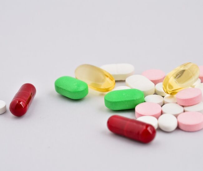 Een verzameling verschillende pillen en capsules op een lichte achtergrond.