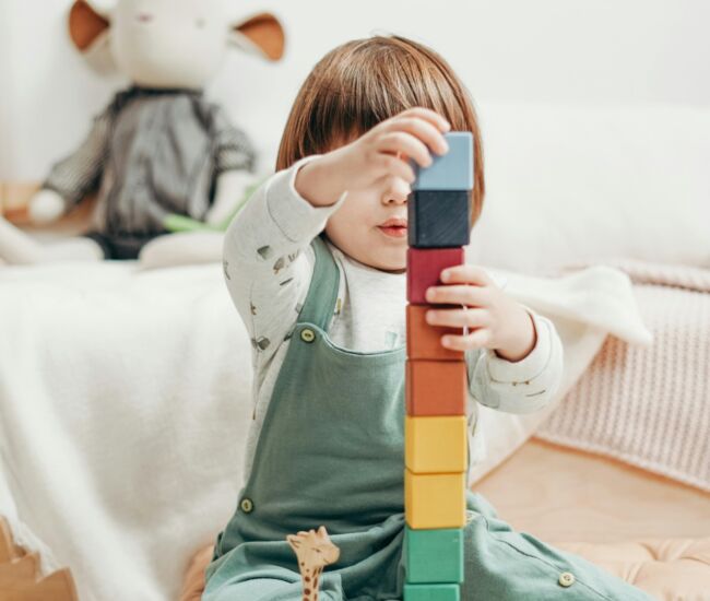Een kind bouwt een toren met kleurrijke blokken.