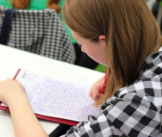 Een meisje schrijft in een notitieboek tijdens een les.