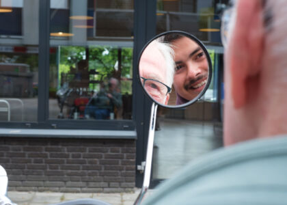 Twee mannen glimlachen naar elkaar in een spiegel.