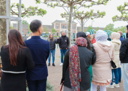 Groep mensen luistert naar een spreker in een park.