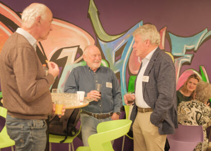 Drie mannen in gesprek met kleurrijke graffiti op de achtergrond.