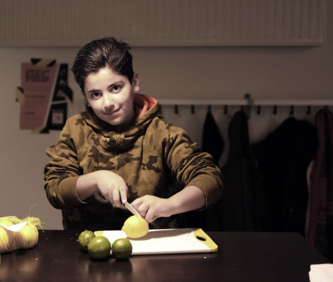 Jongen snijdt citroen op een snijplank in de keuken.