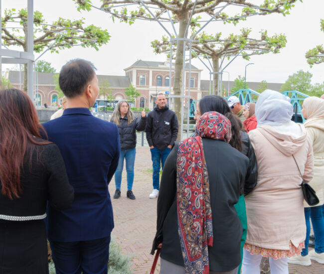 Groep mensen luistert naar een spreker in een park.