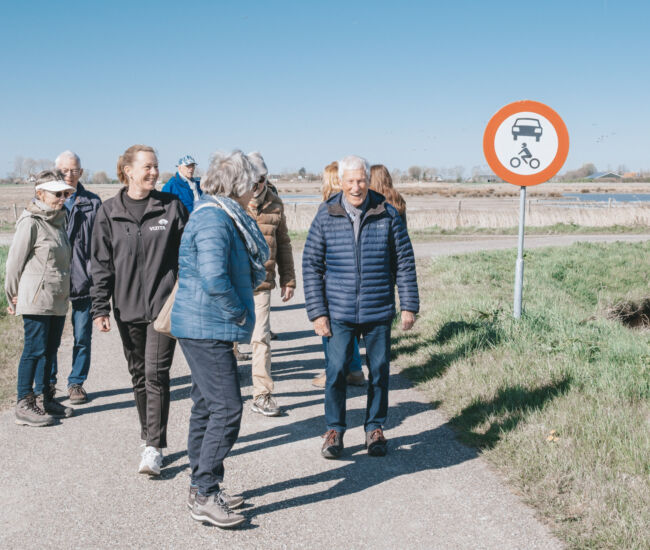 Groep mensen wandelt op een pad met een verkeersbord.
