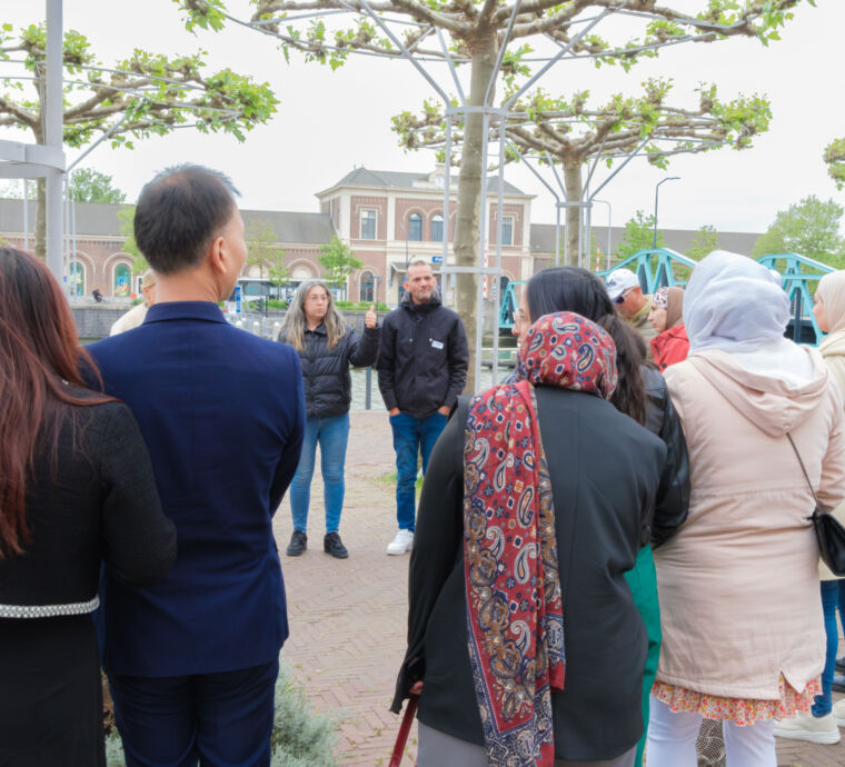 Groep mensen luistert naar een spreker in een park.