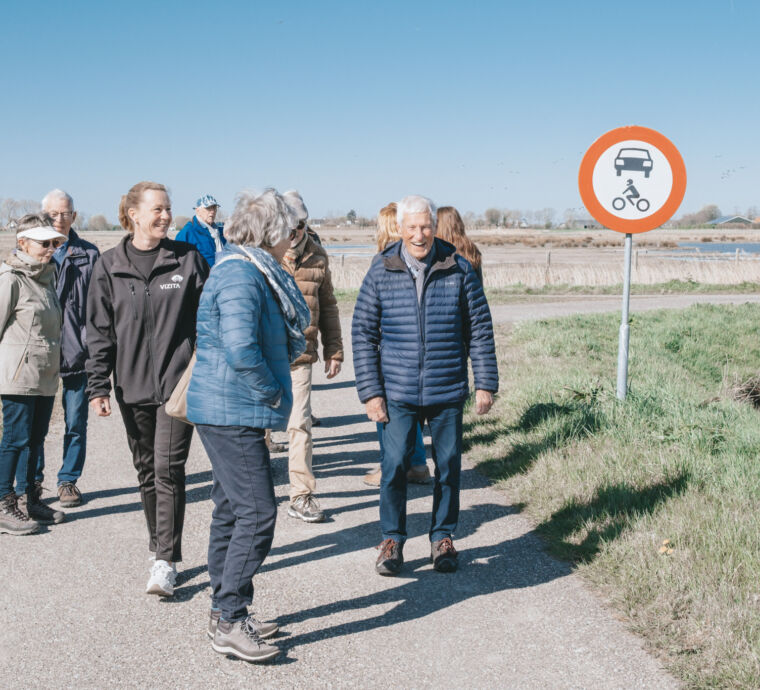 Groep mensen wandelt op een pad met een verkeersbord.