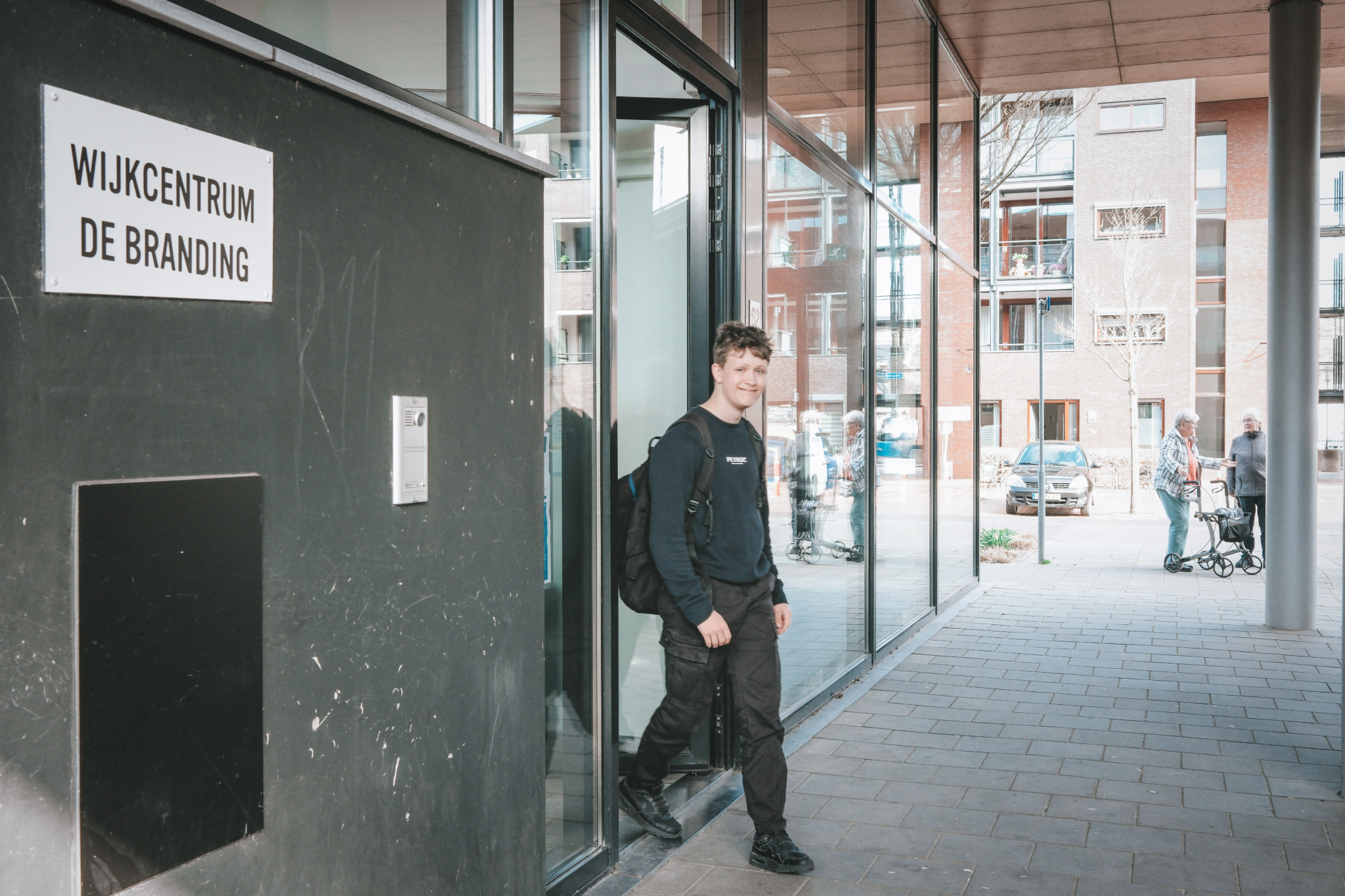 Jongeman verlaat wijkcentrum De Branding met een glimlach.