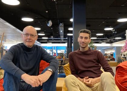 Twee mannen zitten op zitzakken in een moderne ruimte.