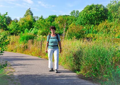 Een vrouw wandelt op een pad omringd door groen.