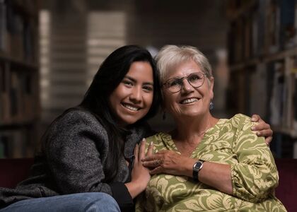 Een jonge vrouw en een oudere vrouw poseren samen en lachen.