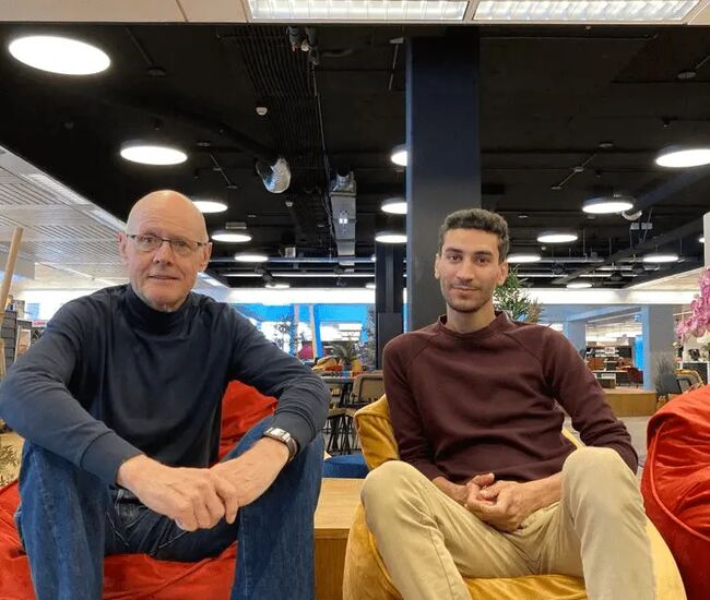 Twee mannen zitten op zitzakken in een moderne ruimte.