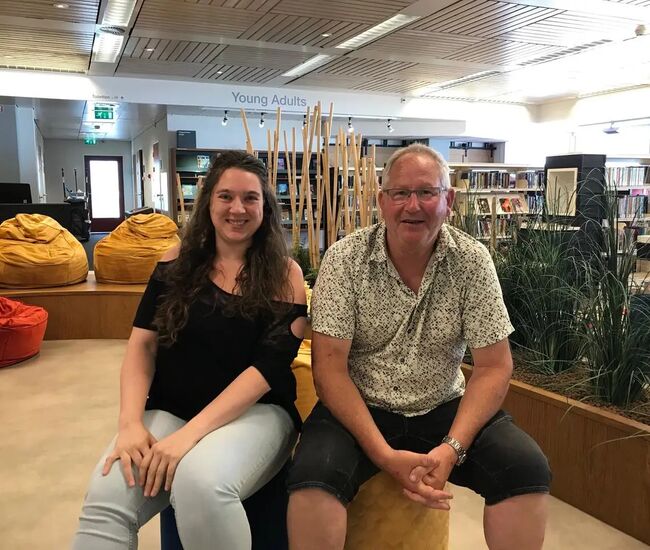 Twee mensen zitten op kleurrijke zitzakken in een bibliotheek.