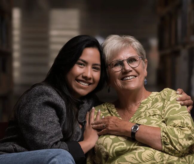 Een jonge vrouw en een oudere vrouw poseren samen en lachen.