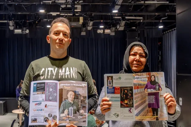 Twee mensen houden informatiemateriaal vast over een evenement in Middelburg.