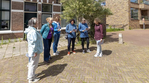 Groep vrouwen staat buiten en bekijkt kaarten of brochures.