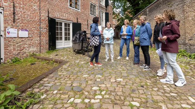 Groep mensen luistert naar een gids in een historische straat.