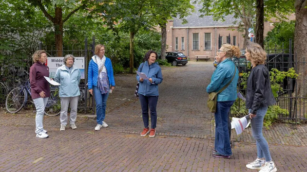 Groep mensen in gesprek op een straat met bomen en fietsen.