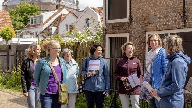 Groep vrouwen luistert naar een gids tijdens een stadswandeling.