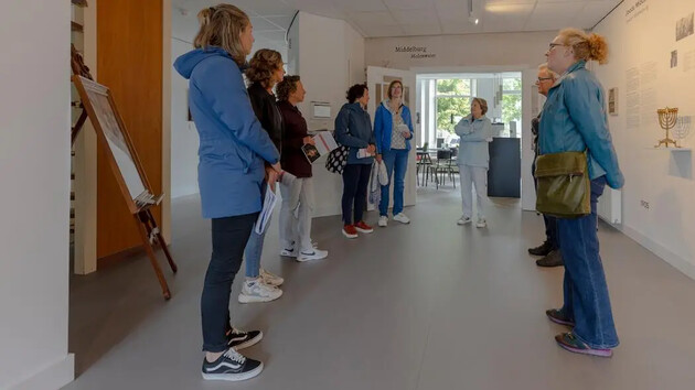Groep mensen luistert naar een rondleiding in een museum.