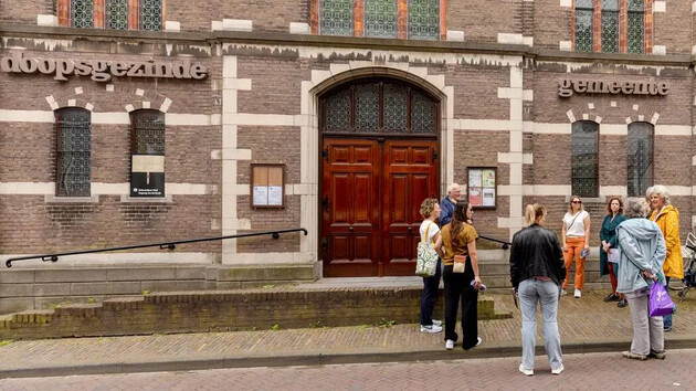 Groep mensen voor de ingang van een historische kerk.