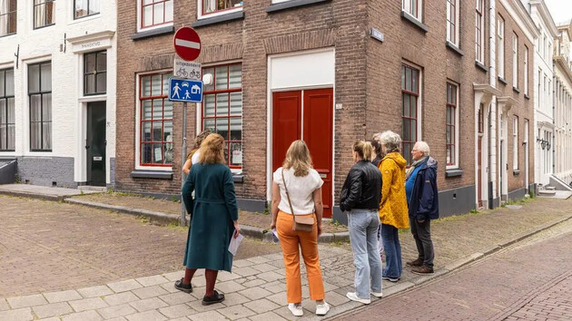 Groep mensen kijkt naar een gebouw met een rode deur.
