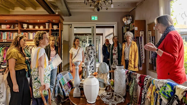 Groep mensen luistert naar een presentatie in een winkel vol decoraties.