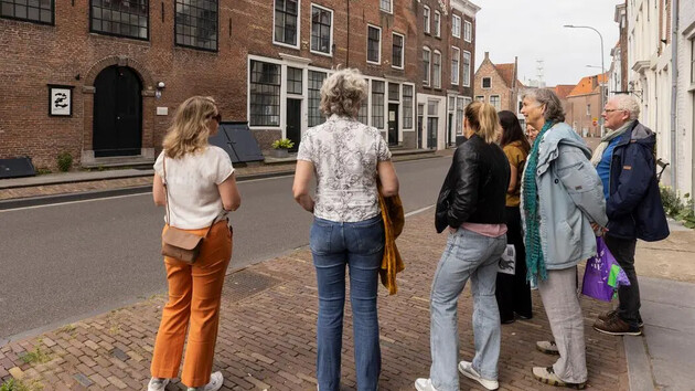 Groep mensen kijkt naar een gebouw aan de straat.
