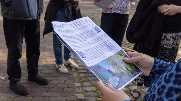 Een persoon houdt een informatief document vast, omringd door anderen.