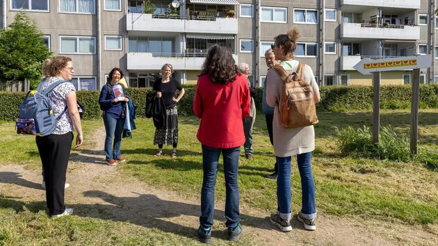 Groep mensen in gesprek op een grasveld voor appartementen.
