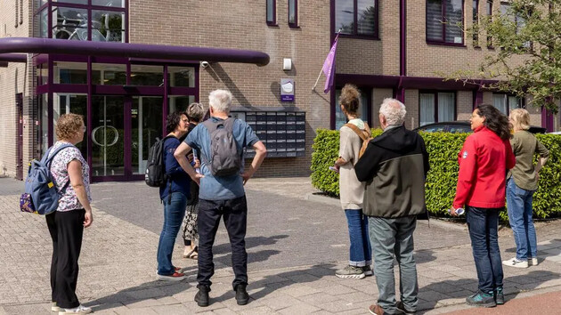 Groep mensen staat voor een gebouw met een paarse ingang.