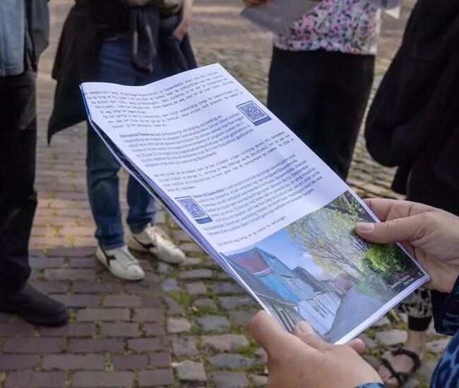 Een persoon houdt een informatief document vast, omringd door anderen.